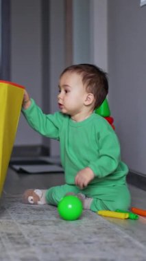 Sevimli bebek büyük sarı bir oyuncak kutusuna uzanıyor. Sevimli çocuk oyuncakları kutudan almak istiyor. Dikey video