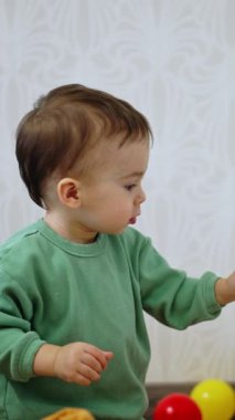 Dolabın önünde yerde oturan meraklı çocuk. Bebek içeri bakarak kapıyı açıyor. Dikey video