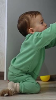 Şirin çocuk odadaki dolabın kapısını açıyor. Evi keşfeden meraklı bir bebek. Dikey video