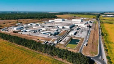 Sarı tarımsal alanda bulunan büyük bir fabrikanın bölgesi. İnsansız hava aracı görüntüleri şehrin dışındaki geniş açık alanda modern girişimin görüntüsünü ortaya çıkarıyor..