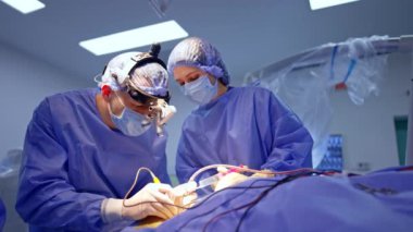 Dikkatli erkek beyaz cerrah elektrikli cerrahi aletler uygular. Hemşire enstrümanı doktora verir..