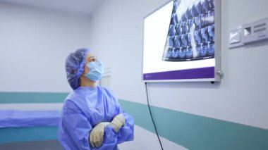Mavi üniforma, şapka ve maske giyen kadın doktor. Sağlık ekibi MRI taramasına bakıyor..