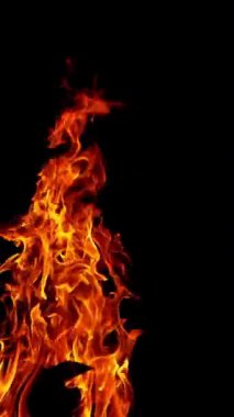 Şenlik ateşi geceleri yanıyor. Ağır çekimde siyah arka planda alevler. Dikey video