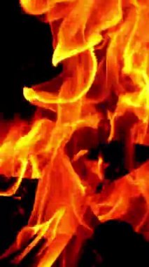 Karanlıkta şenlik ateşinde yavaş çekim, yakın çekim. Şenlik ateşi kıvılcımları ve gece közleri. Dikey video