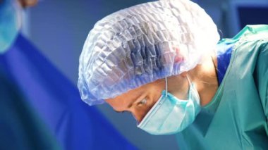 Maskeli ve şapkalı kadın doktor hastaya doğru eğildi. Kafkasyalı bir cerrahın yakın plan portresi bir hastaya odaklanmış..