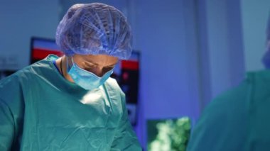 Maske, kep ve mavi bornoz giyen kadın cerrah. Ameliyat odasında çalışan bir doktorun portresi..