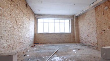 Kırmızı tuğlalı duvarları ve geniş pencereli boş bir oda. Beyaz tuğlalardan yeni inşa edilmiş duvarlar bu önermenin içinde..