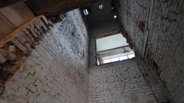 Binanın yıkılan ya da yeniden inşa edilen eski bir asansör boşluğu. Kalitesiz tuğla duvarlı bir oda. Düşük açı görünümü.
