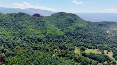 Dağları saran yemyeşil bir yer. Güneşli bir günde, kayalık panorama üzerinde İHA görüntüleri.