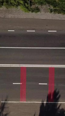 Yoldan kırmızı işaretli ve yaya geçidi olan arabalar geçiyor. Hava görüntüsü. Sağ dikey video için kamera hareketi