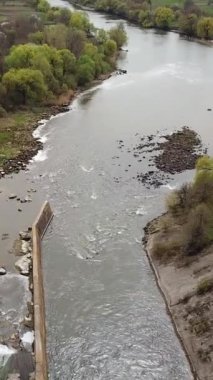 Nehrin iki yakasını ve kanalizasyon arıtma tesisini yazın yüksek bir yerden görmek. Kenar mahallelerin manzarası kuş bakışı. Kamera hareketi azaldı. Hava görüntüsü. Dikey video