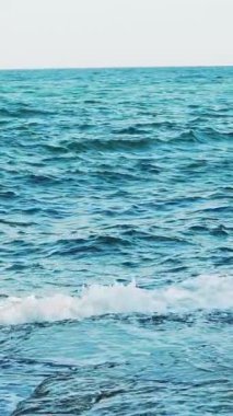 Yazın kıyıya yakın resiflerde dalgaların tepeleri kırılıyor. Deniz Burnu. Ağır çekim. Hava görünümü Dikey video