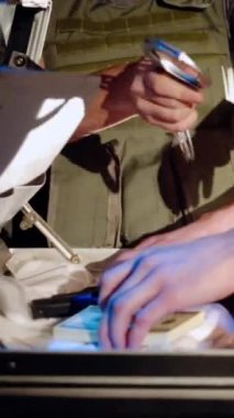 Formda bir polis, suç mahallinde bir gangsteri uyuşturucu dolu bir bavulun yanında tutukluyor. Polis kelepçeleri. Uyuşturucu bağımlılığı. Dikey video