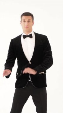 Siyah takım elbiseli komik adam beyaz arka planda dansçı dansını gösteriyor.