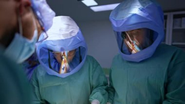 Koruyucu kask takan iki erkek doktor hastaya odaklanmış görünüyor. Profesyoneller travmayı ameliyat ederler..