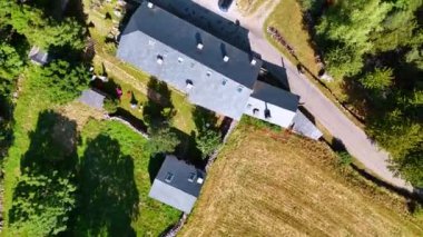 Gri çatıları olan evlerin üzerinde yükseliyor ve daireler çiziyor. Villanın yakınındaki kırsal ve otlaklar..