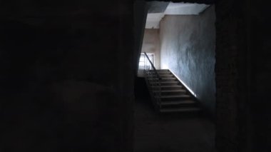 İnşaat halindeki binanın koridorunun yanından geçiyor. Odanın içinde beton dolu çuvallar var..