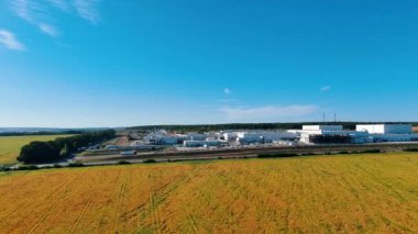 Kırsal alana yayılmış büyük ve modern bir bitkinin bölgesi. Mavi gökyüzü ve sarı arazi arasında büyük bir girişim..