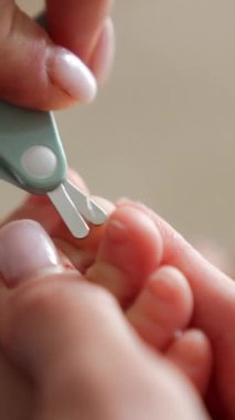 Küçük bir bebek için ayak tırnaklarını kesiyorum. Şefkatli anne prosedür için özel makası kullanıyor. Kapatın. Arkaplan bulanık. Dikey video