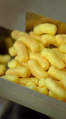 Puff corn yaklaşıyor. Tatlı altın mısır çubuğu fabrikası. Dikey video