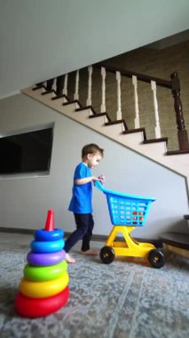 Bebek çocuk arabadan bir yüzük alır ve onu piramit tabanına yerleştirir. Çocuk evde oyuncaklarla oynuyor. Dikey video.