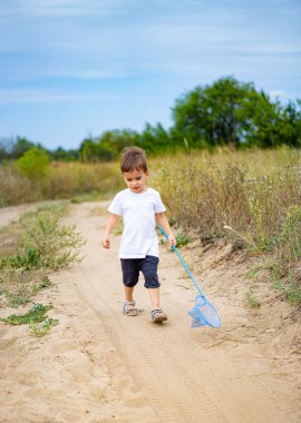 Çocuk elinde bir ağla dışarıyı keşfediyor. Genç çocuk kumlu bir yolda yürüyor, neşeli bir şekilde doğada böcek arıyor, yeşillik ve mavi gökyüzü ile çevrili..