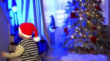 Mutlu beyaz çocuk Noel Baba şapkası takıyor ve neşeyle odada zıplıyor. Noel kutlaması neşesi.
