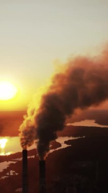 Yüksek voltaj direği. Yüksek voltajlı gökyüzü arka planı, üzerinde duman olan fabrika borusu. Dünya kirliliği ve sanayileşme kavramı. Seçici odaklanma. Dikey video