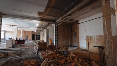 Geniş alandaki tuğla yığınları, diğer malzemeler ve enkaz yığınları. Binanın etrafında yeniden inşa edilen bir tur..