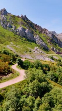 Dalgalı yol, manzaralı dağlık araziyi geçiyor. Dağlık bölgede olağanüstü bir doğa. Dikey video.