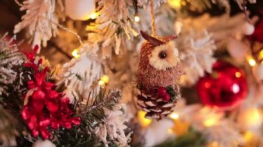 Karla süslenmiş yapay köknar ağacının bir parçası. Dalda asılı duran kozalağın üzerinde güzel bir baykuş dekoru. Kapat..