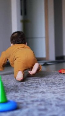 Küçük çocuk oyuncağa ulaşmak için hızla odanın yanından geçiyor. Mutlu çocuk kırmızı yüzüğü alır ve annesine götürür. Dikey video