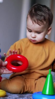 Annesinin eli, bir piramitten kırmızı bir yüzük alıp oğluna veriyor. Çocuk bir oyuncak aldı ve yere fırlattı. Kara kedi arkadan yaklaşıyor. Dikey video