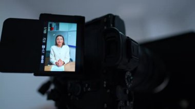 Profesyonel kamera, beyaz bir kadının konuşmasını çekiyor. Ekipmanlardan yavaşça uzaklaşın. Bulanık arkaplan.