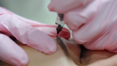 Dövme ustası müşterinin kaşlarına ince çizgiler uygular. Kuaförde güzellik prosedürü uyguluyorum. Kapat..