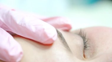 Pembe lateks eldivenli eller dövme aleti kullansın. Usta kaş mikro bıçaklama sanatını icra ediyor. Kapat..