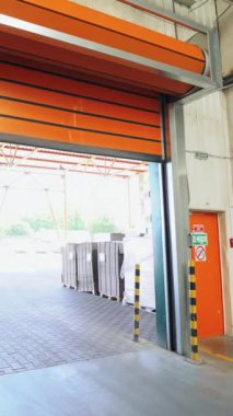 Otomatik turuncu kapılar ahşap fabrikası deposuna iniyor. Kamera sağa doğru hareket ediyor. Dikey video
