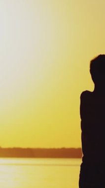 Küçük çocuk elinde kağıt uçağın origamisini tutuyor ve gün batımında gölün arka planında çalıyor. Bir çocuk kağıt oyuncağıyla oynamak için yanıp tutuşuyor. Dikey video