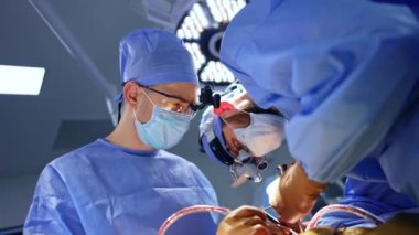 İki ortak çalışan beyin cerrahı ameliyat için cerrahi alet kullanıyor. Ameliyat yapan profesyonel doktorlara düşük açılı bakış açısı.