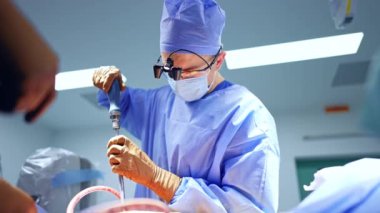 Cerrahi loplardaki beyin cerrahı ameliyatta tornavida kullanıyor. Cerrahide çalışan doktora düşük açılı bakış açısı.