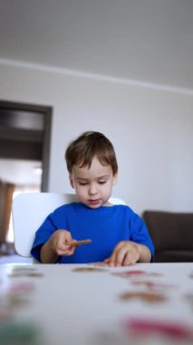 Sevgili erkek bebek yapboz parçalarını birleştiriyor. Mutlu çocuk ayrıntılar eşleştikçe sevinçle alkışlıyor. Düşük açı. Dikey video.