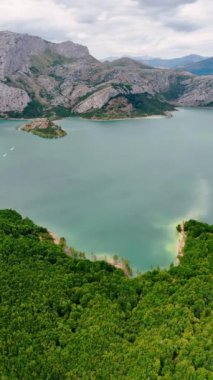 Dağlık yabanın nefes kesici manzarası. Ayağında kayalar ve göl olan güzel doğanın manzarası. Dikey video.