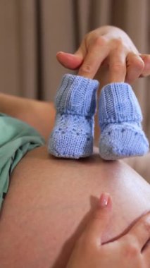 Kafkasyalı kadının yatakta oturup hamileliğin tadını çıkarması, fotokopi odası. Evde bebek poposu olan hamile bir kadın. Dikey video