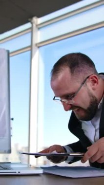 Dizüstü bilgisayarda yazan komik bir iş adamı. Gözlüklü bir ofis çalışanı iş yerinde masasında oturmuş suratını asıyor. İşle ilgili sorunlar. Dikey video