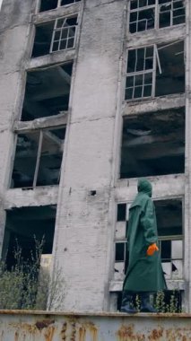 Maskeli ve kimyasal koruyucu giysili bir laboratuvar teknisyeni kuru zeminde yürüyor ve çevreye bakıp kirliliği düşünüyor. Ekolojik felaket konsepti. Dikey video