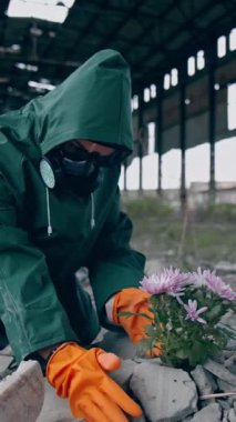 Gezegenimize yeni bir hayat vermek. Güvenlik giysisi ve gaz maskesi takmış bir ekolojist. Binanın etrafındaki çöplüğe çiçek koymaya hazırlanıyor. Biyokimyasal saldırı konsepti. Dikey video