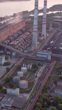 Gün batımında ağaçlar ve yolun arka planında yüksek gerilim hatları olan bir site. Kamera hareketi ileri. Hava görüntüsü. Dikey video