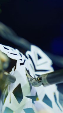 Metal cyborg, Noel 'e hazırlanırken kağıttan kar tanelerini hazırlıyor. Kesik manzara. Robot endüstrisi konsepti. Dikey video