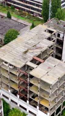 Bir fabrikada penceresi olmayan bitmemiş eski bir bina. Boş binaları ve depoları olan terk edilmiş sanayi bölgesi. Hava görüntüsü... dikey video