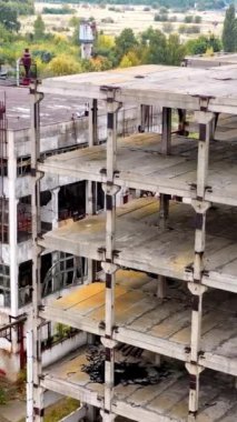 Bitmemiş bir endüstri binası. Penceresi olmayan eski bir fabrikanın dış cephesi. Savaş sonrası yıkılmış mimari... dikey video.